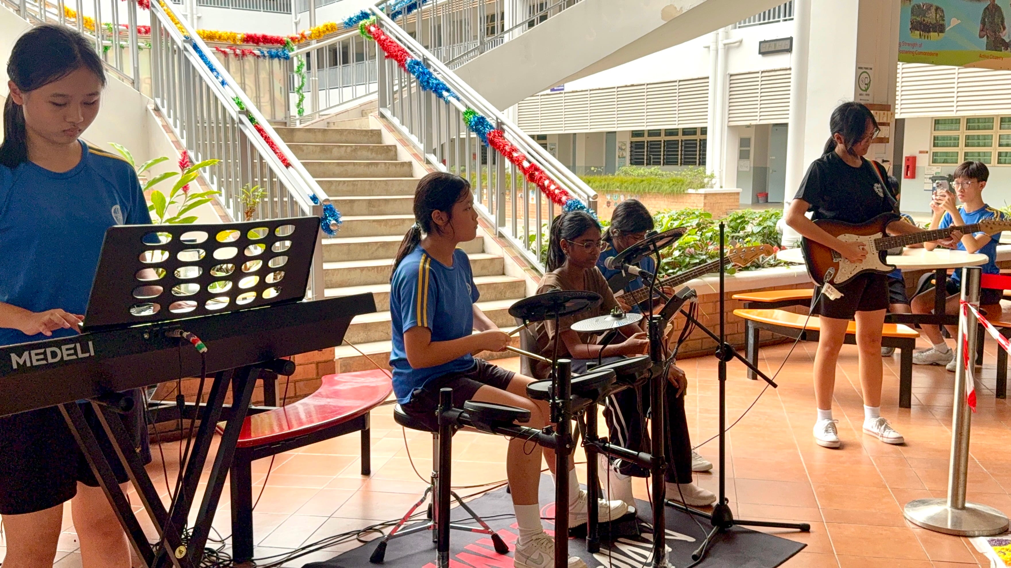 Open mic lunch time performance: A group of dedicated students confidently showcase their musical talents, filling the space with melodies.